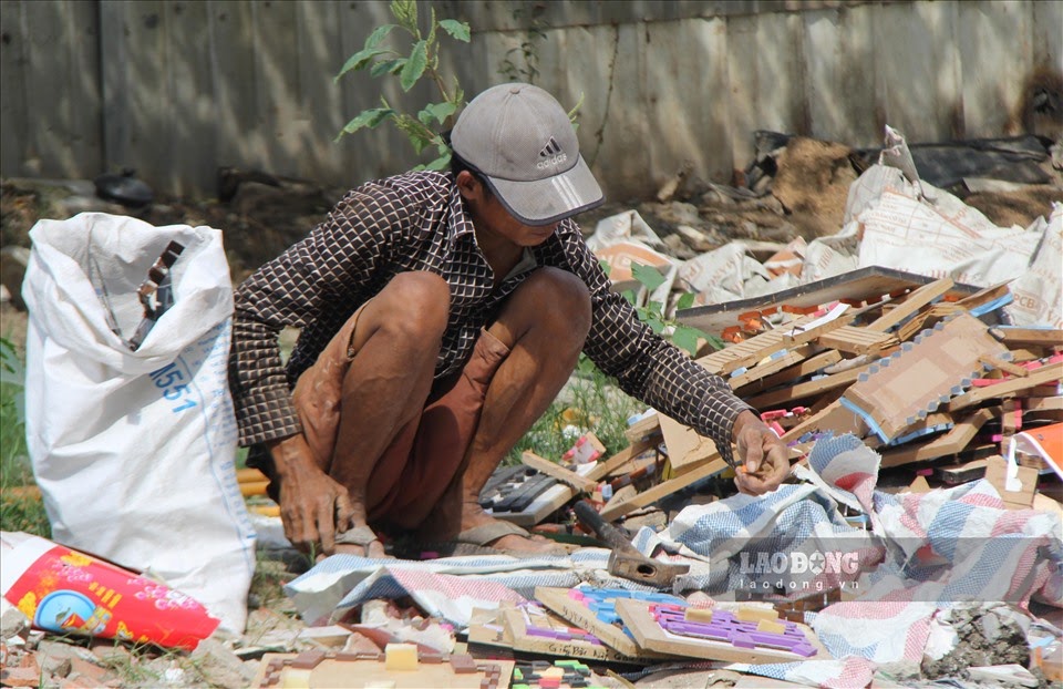 Một người lao động tự do đang nhặt ve chai từ b&atilde;i r&aacute;c. Ảnh: B&aacute;o Lao Động.