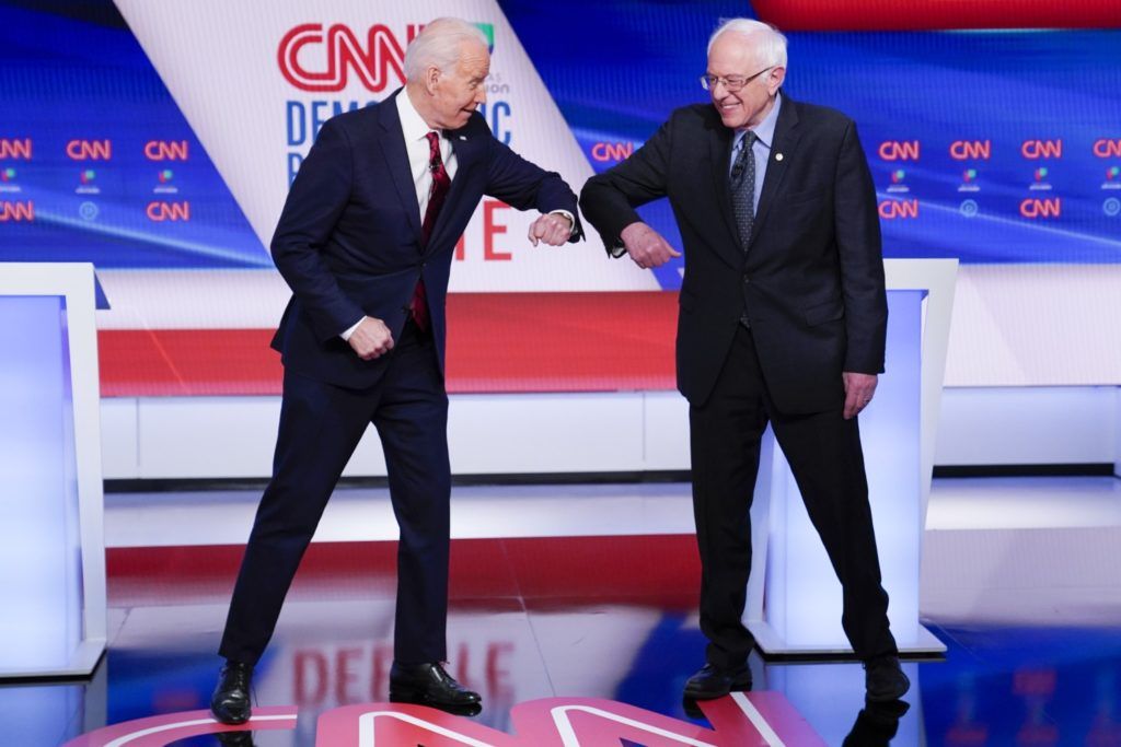 Hai ứng viên của Đảng Dân chủ, Joe Biden và Bernie Sanders đụng cùi chỏ tay thay vì bắt tay như thông lệ. Ảnh: CNN.