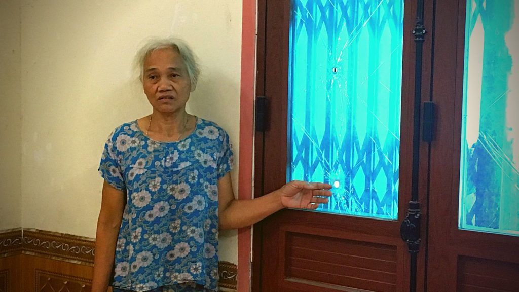 Bà Dư Thị Thành và vết đạn bắn trên cửa kính. Ảnh: May/Luật Khoa.