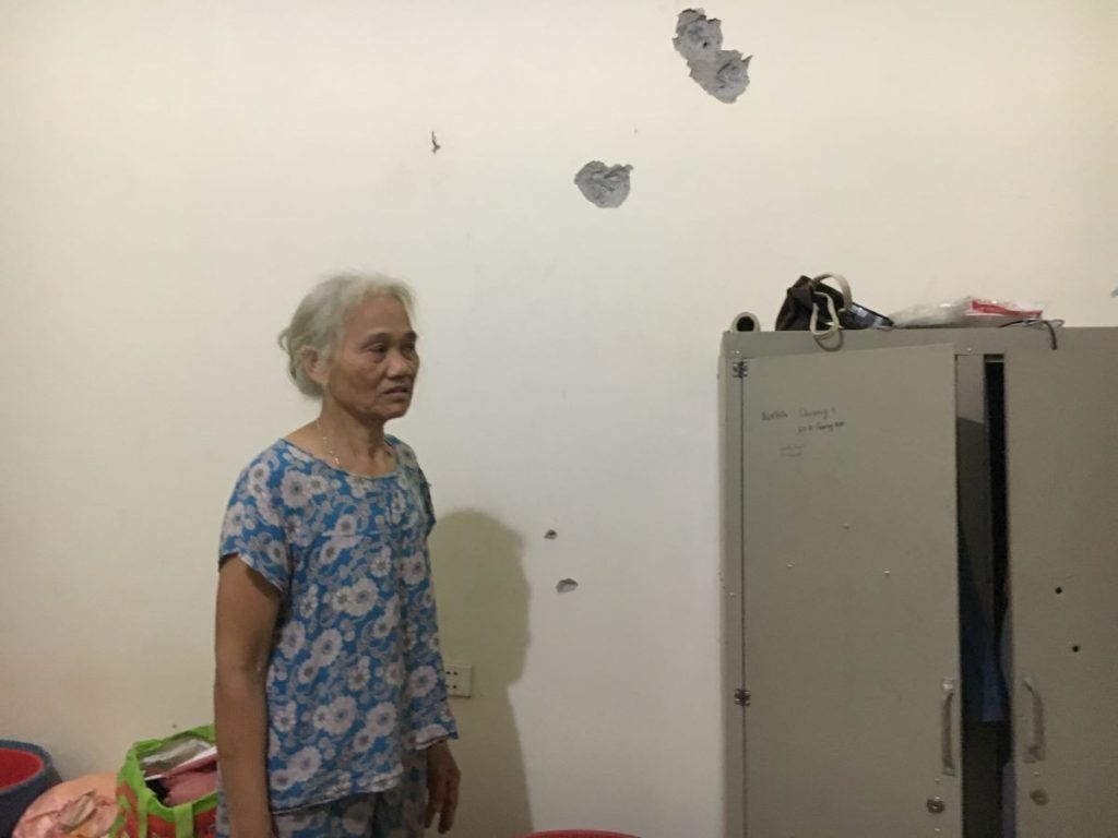 Bà Dư Thị Thành và những vết đạn bắn hằn lên tường nhà. Ảnh: May/Luật Khoa.