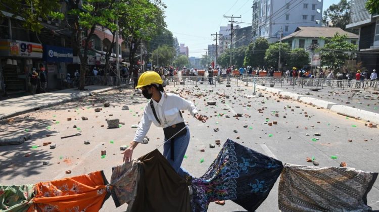 Một người biểu tình giăng sợi dây treo các trang phục của phụ nữ chắn ngang đường trong cuộc biểu tình tại Yangon vào ngày 8/3/2021. Ảnh: STR/ AFP.
