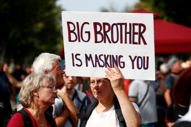 “Anh Cả đang đòi đeo khẩu trang cho bạn đấy”, một người biểu tình với biểu ngữ nhại lại câu nói nổi tiếng trong tác phẩm 1984 của George Orwell. Ảnh: Reuters.