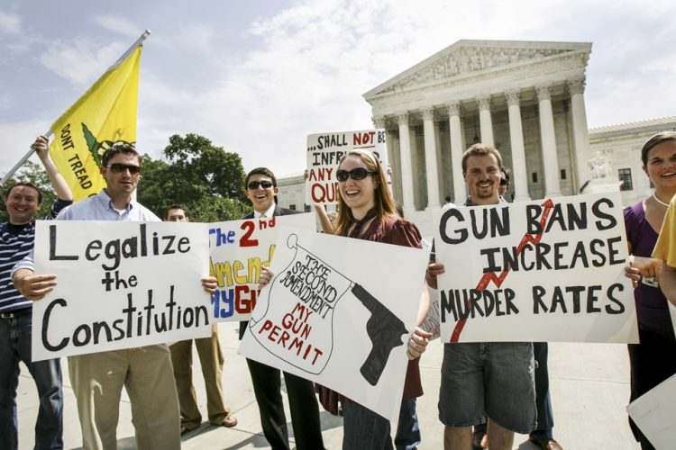 ** FILE ** In this June 26, 2008 file photo, pro-rights gun supporters hold up banners outside the Supreme Court in Washington after the court ruled  that Americans have a constitutional right to keep guns in their homes for self-defense.  Criminal defense lawyers say the high court's decision means federal laws designed to keep guns out of the hands of people convicted of felonies and crimes of domestic violence are unconstitutional as long as the weapons are needed for self-defense.  (AP Photo/Jose Luis Magana, File)