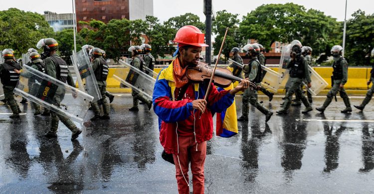 Một người biểu tình Venezuela chơi vĩ cầm giữa cuộc xuống đường phản đối Tổng thống Nicolas Maduro, tháng 5/2017. Ảnh: Federico Parra/AFP/Getty Images.