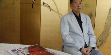 Jimmy Lai ngồi bên cạnh tờ báo Apple Daily số ra ngày 1/7/2020. Ảnh: Vincent Yu/AP Photo.